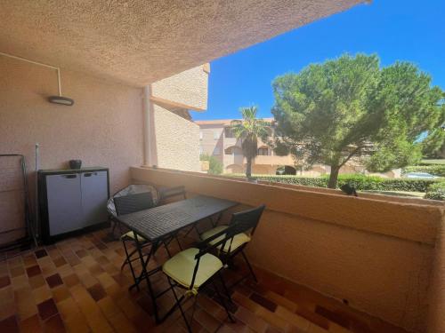 un balcon avec une table, des chaises et une fenêtre dans l'établissement T2 Proche Plage, à Carqueiranne