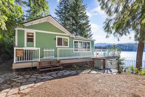 a green house with a deck and a body of water at Lakeside Loungin' in Hayden
