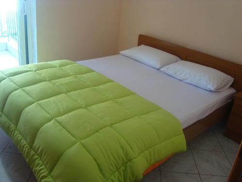 a bed with a green blanket on top of it at Zavrakli in Agia Paraskevi