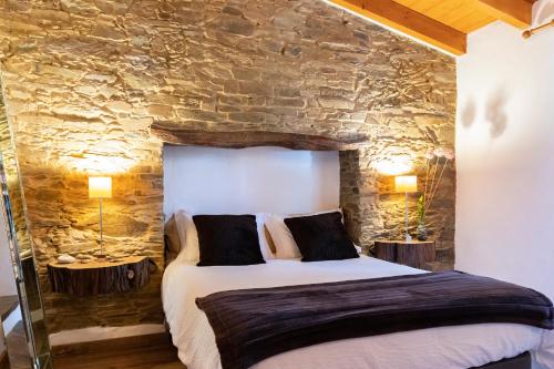 a bedroom with a bed and a stone wall at Casas de Campo do Castro da Cola in Marchicão