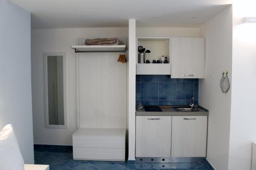 a small kitchen with white cabinets and a sink at Divina Holiday - Apartments in Maiori