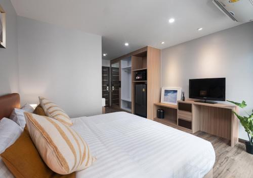 a bedroom with a large white bed and a flat screen tv at VSK RESIDENCE - SHA Extra Plus in Lat Krabang