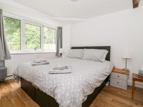 Claire Cottage في سيلبي: غرفة نوم مع سرير كبير مع ملاءات بيضاء ونوافذ