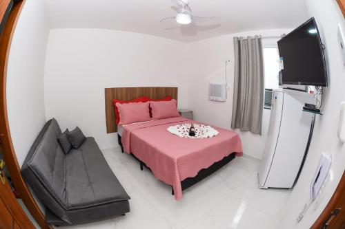a small bedroom with a pink bed and a tv at Pousada Central de Arraial in Arraial do Cabo