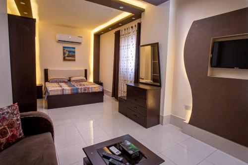 a living room with a bed and a television at Al Riyati Hotel Apartments in Aqaba