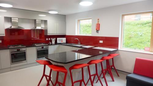 a red kitchen with a black counter and red stools at Tyler Court, University of Kent in Canterbury