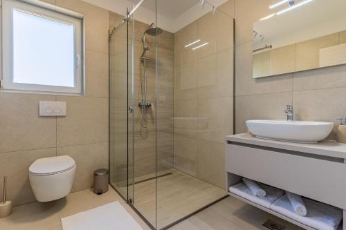 a bathroom with a toilet and a sink and a shower at Villa Orhideja in Cres