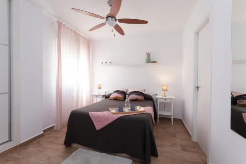ein Schlafzimmer mit einem Bett und einem Deckenventilator in der Unterkunft APARTAMENTO VIRGEN DEL CARMEN in Chipiona