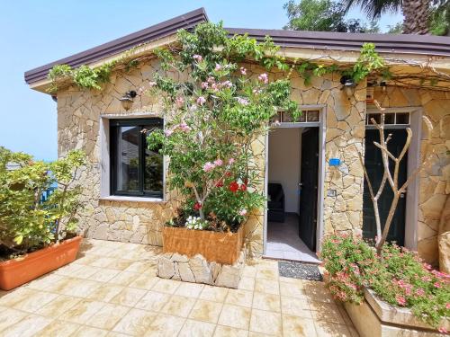 a stone house with plants in front of it at Villa Anita Apartments in Capo dʼOrlando