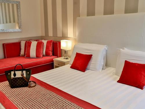 two beds with red and white pillows and a couch at Hotel Tigullio Et De Milan in Santa Margherita Ligure