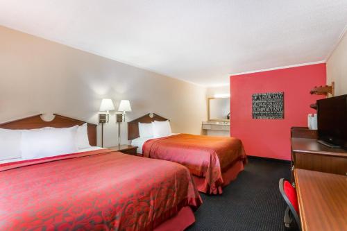 um quarto de hotel com duas camas e uma televisão de ecrã plano em The Inn At Plantation em Weston