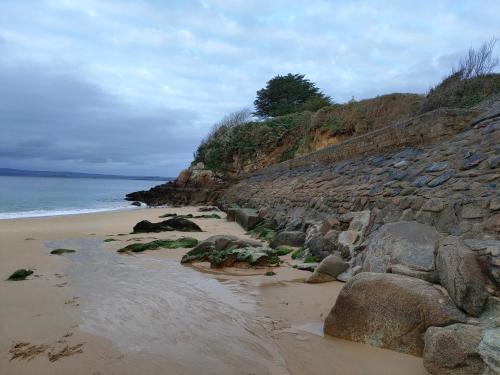 a sandy beach with rocks and the ocean at Maison de pêcheur Port de plaisance Tréboul in Douarnenez