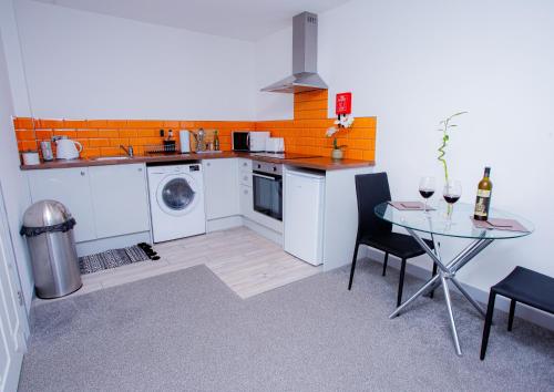 a kitchen with a washing machine and a table with chairs at Cosy Executive City Apartment in Doncaster