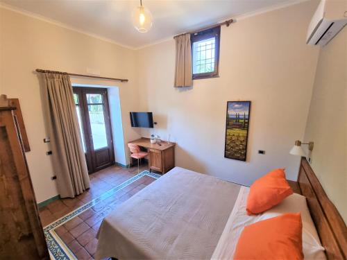 a bedroom with a bed and a desk and a television at Casa Fifina Rooms in Sant'Egidio del Monte Albino