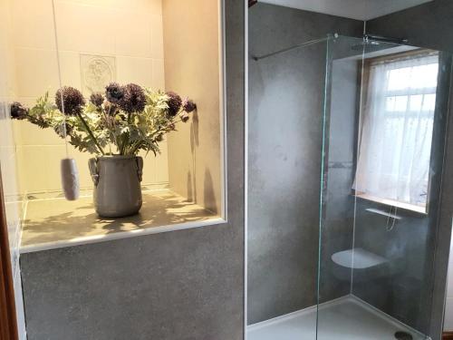 a vase with flowers on a shelf in a shower at Glencoe House Inverness in Inverness