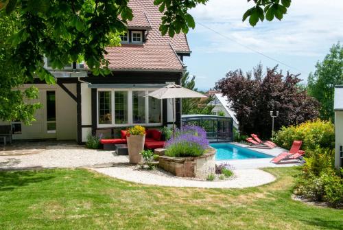 une cour arrière avec une piscine et une maison dans l'établissement La Villa Du Coteau, à Obernai
