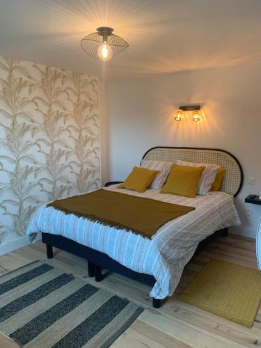 une chambre avec un grand lit avec des oreillers jaunes dans l'établissement Les Remparts de Joussaume Latour, à Château-Thierry