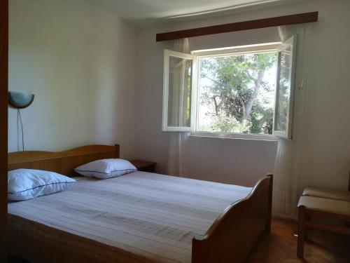 a bedroom with a large bed with a window at Apartment Porat in Ugljan