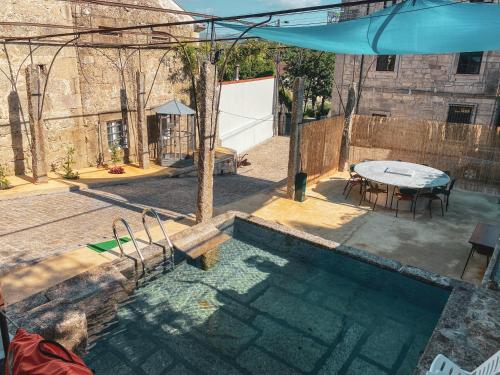 a swimming pool with a table and an umbrella at Casa do Convento in Arcos de Valdevez