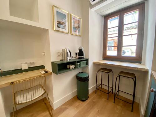 - une petite cuisine avec deux tabourets de bar et une fenêtre dans l'établissement Studio d'architecte centre historique, à Ajaccio