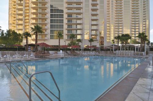 a large swimming pool with chairs and buildings at The Signature at MGM Grand - All Suites in Las Vegas