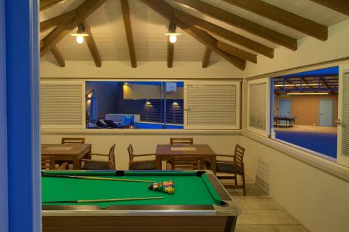 a pool table in a room with tables and chairs at Villa Dora in Bajčići