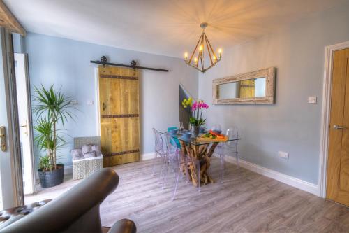 a dining room with a table with chairs and a chandelier at The Rockpool - private hot tub and sea views in Amble