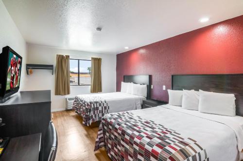 a hotel room with two beds and a red wall at Red Roof Inn Palmdale - Lancaster in Palmdale