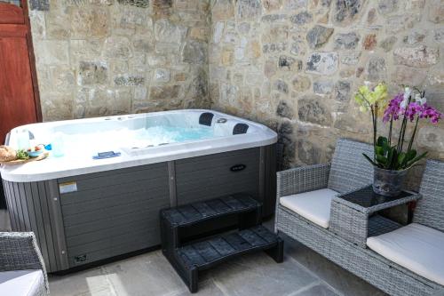a jacuzzi tub in a room with a chair at The Rockpool - private hot tub and sea views in Amble