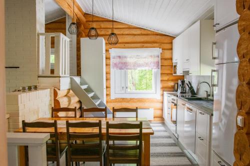 cocina con paredes de madera, mesa y sillas en Loma-Autio Aamurusko, en Puumala