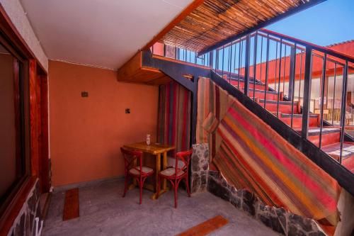 a balcony with a table and two chairs and a staircase at Hotel Casa Algarrobo in San Pedro de Atacama