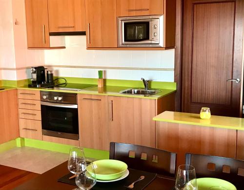 a kitchen with wooden cabinets and a table with green accents at VIVIENDA CORRUBEDO VISTA DUNAS in Corrubedo