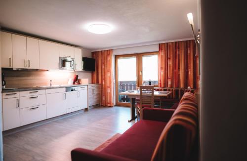 a kitchen with white cabinets and a table with a dining room at SennHOF Lechtal in Bach