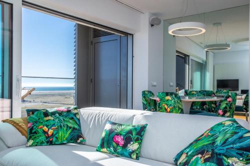 a living room with a white couch with tropical pillows at Ocean 52 by Rent4All in Figueira da Foz