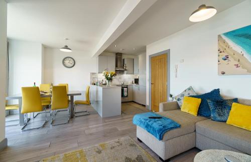 a living room and kitchen with a couch and a table at Portrush Penthouse in Portrush
