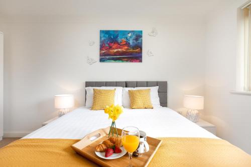 a bed with a tray of food and drinks on it at KVM - Peacock Apartment close to town by KVM Stays in Peterborough