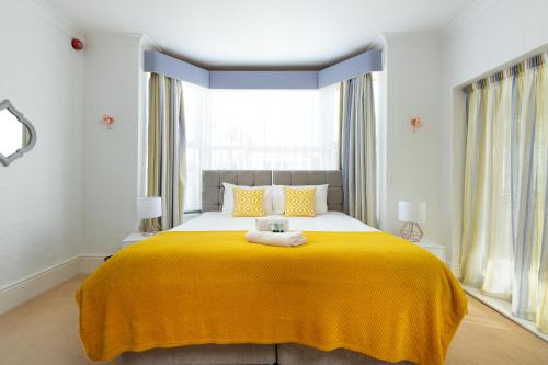 a bedroom with a large bed with a yellow blanket at KVM - Sugar Way House for large groups by KVM Stays in Peterborough