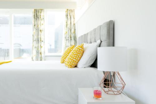 a white bedroom with a bed with yellow pillows at KVM - Sugar Way House in Peterborough