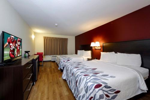 a hotel room with two beds and a flat screen tv at Red Roof Inn Osage Beach - Lake of the Ozarks in Osage Beach