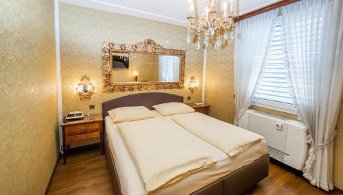 a bedroom with a large bed and a mirror at Hotel Palais Porcia in Klagenfurt
