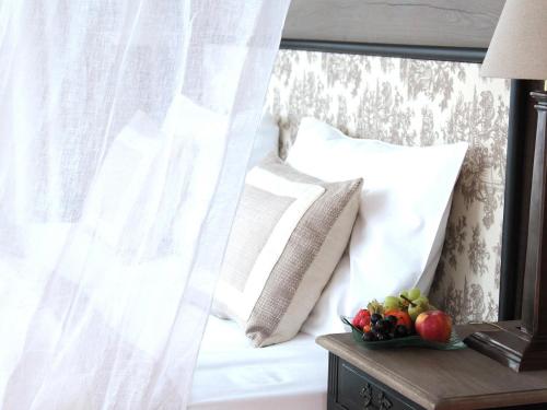 a bed with white curtains and a bowl of fruit on a table at Alpin Resort Sacher in Seefeld in Tirol