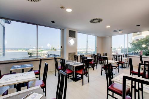 a restaurant with tables and chairs and large windows at Hotel Vela d'Oro in Rimini