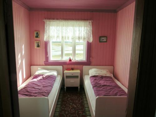 2 camas en una habitación con paredes rosas y ventana en Húsey Hostel & Horsefarm, en Egilsstadir