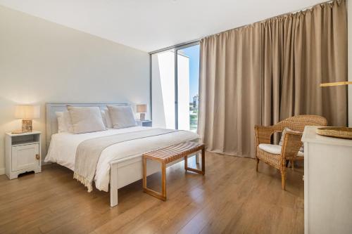 a white bedroom with a bed and a window at Sagres Blue Villa H - 10 min walk to the beach in Sagres