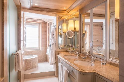 a bathroom with two sinks and a tub and a mirror at Alpin Resort Sacher in Seefeld in Tirol