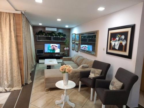 a living room with a couch and chairs and a tv at Guest House Maja in Novi Sad
