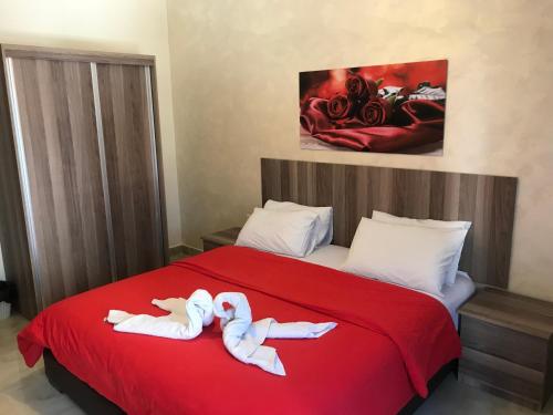 a bedroom with two people laying on a red bed at Suzan Hotel Apartments in Amman