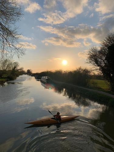 a person in a kayak on a river at sunset at Rew Farm Country & Equestrian Accommodation - Sunrise Lodge in Melksham