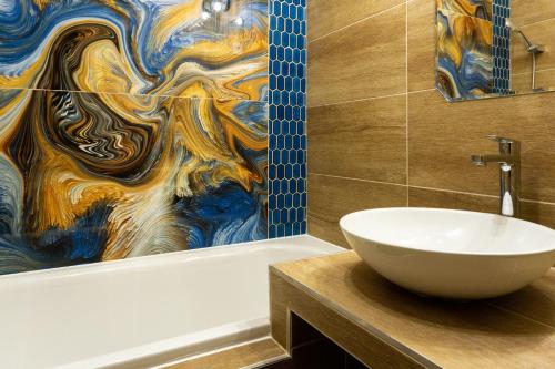 a bathroom with a sink and a bath tub with a painting at Secret Garden Apartman in Miskolc