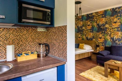 a kitchen with a sink and a living room at Secret Garden Apartman in Miskolc